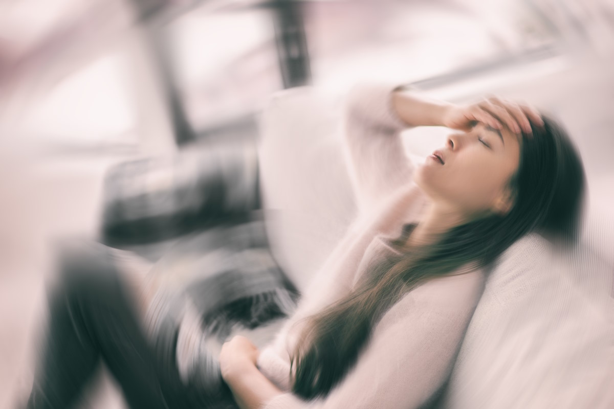 Femme assise se portant la main à la tête, effet graphique dynamique, sensation de vertige